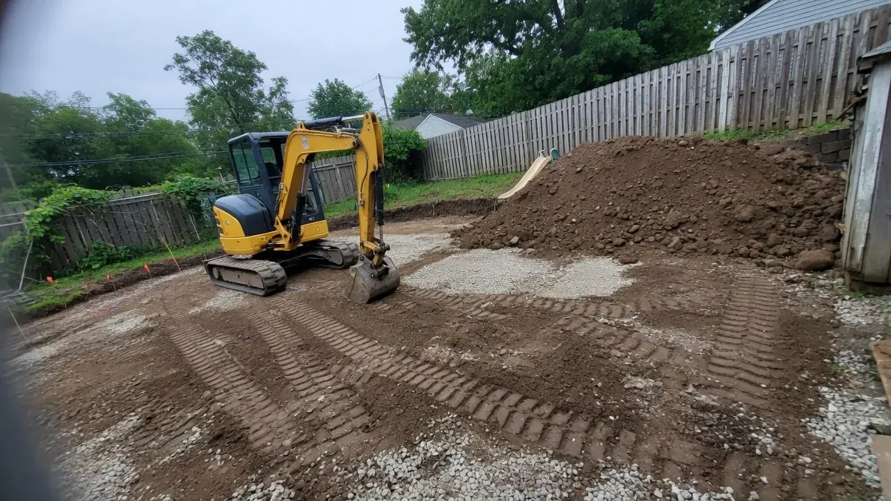 Compact excavator grading a residential site before paving