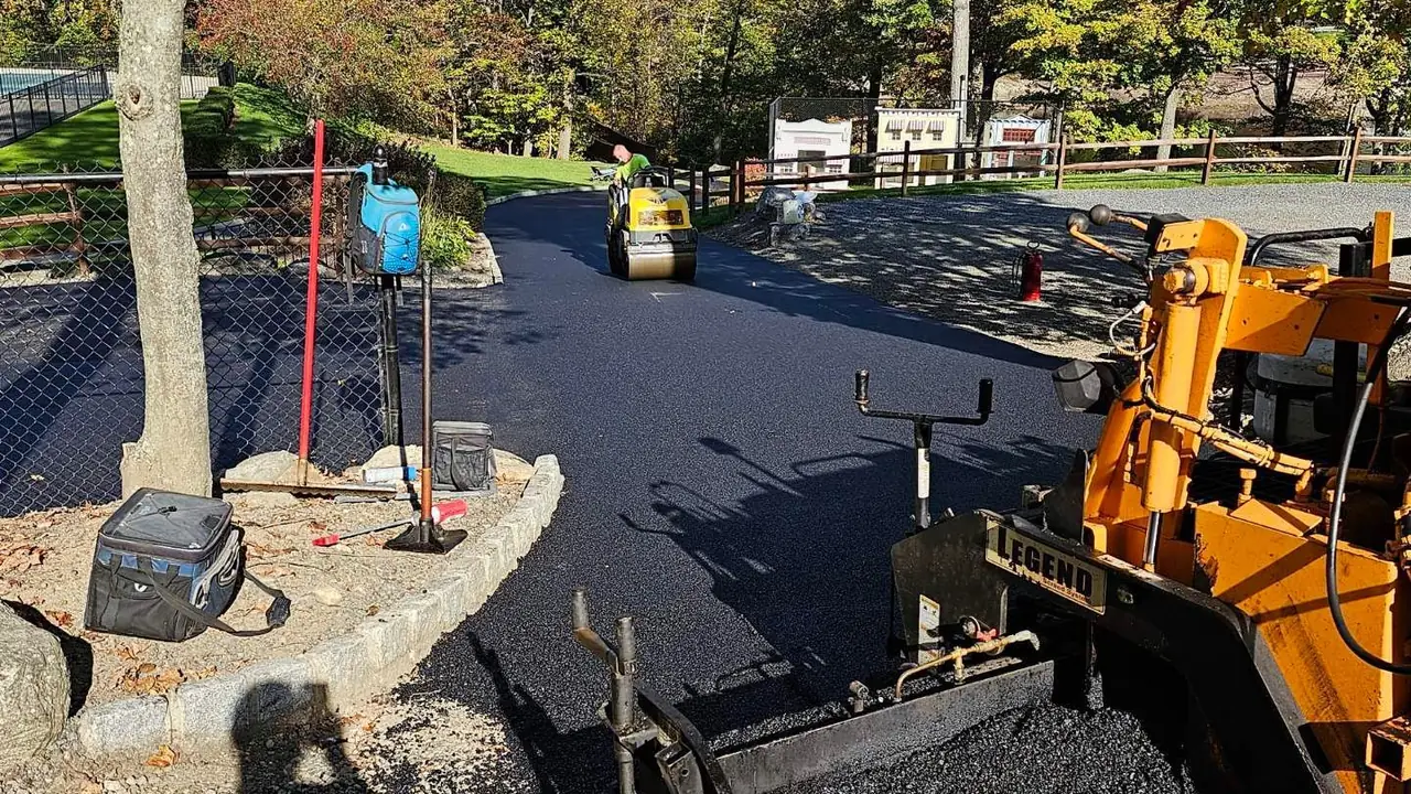 Asphalt paver and roller working a village road repaving job