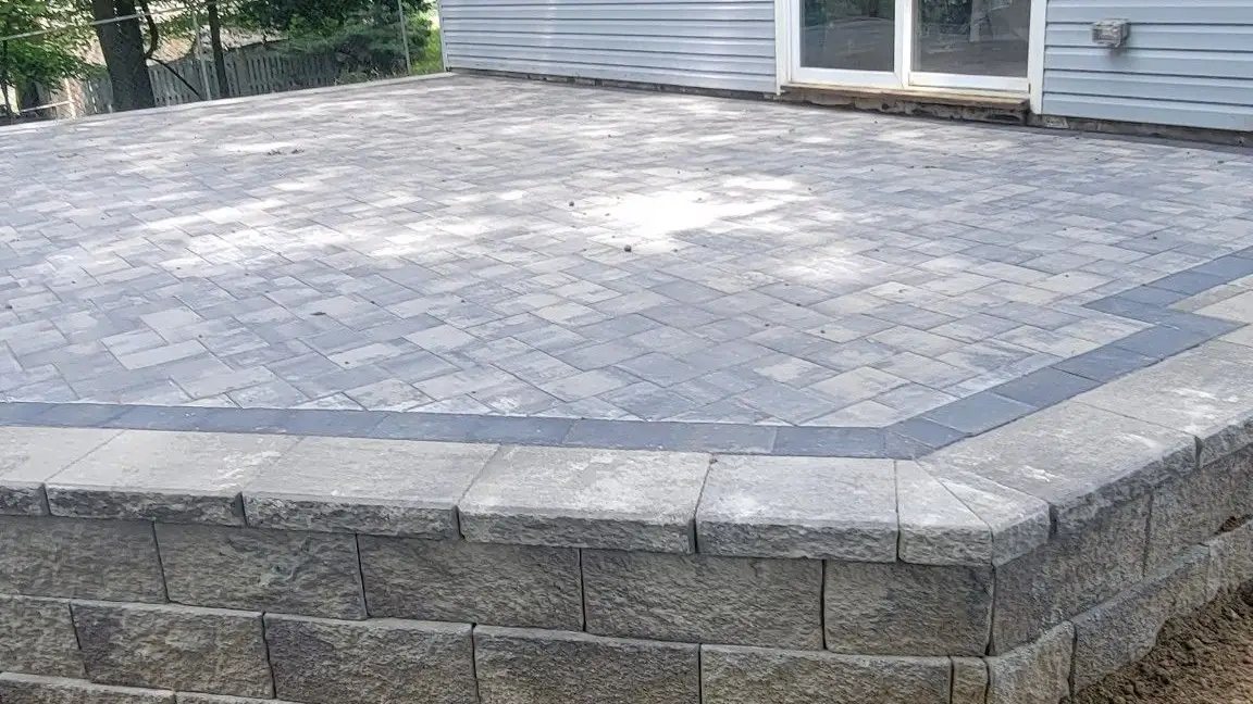 Paver patio and block retaining wall behind a New Jersey home