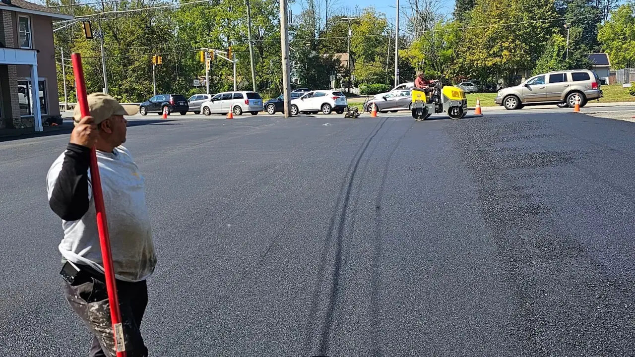 Crew member raking a newly paved commercial parking lot