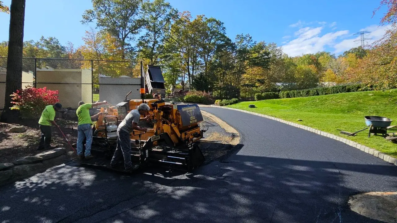 Asphalt paver and crew laying a fresh mat on a private road