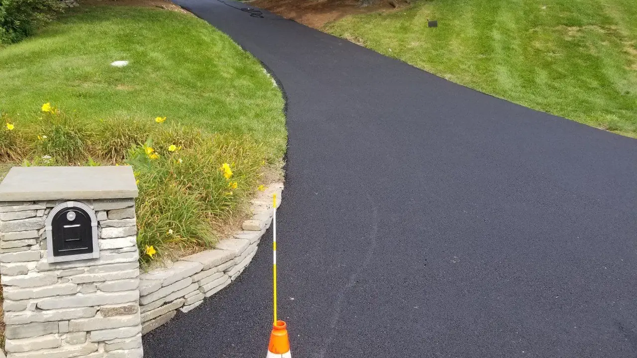Curved residential asphalt driveway with a stone mailbox pillar