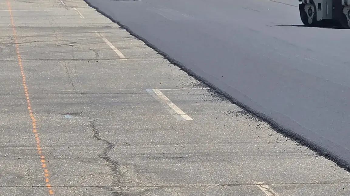 Freshly resurfaced asphalt beside the failed original lot surface