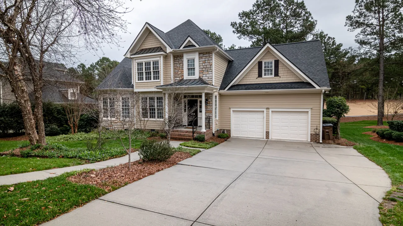 Two-story house with a wide concrete driveway leading to a two-car garage